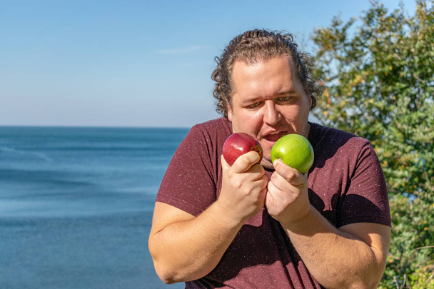 Hombre gordo divertido en el océano comiendo frutas. Vacaciones, pérdida de peso y alimentación saludable
 - Foto, imagen