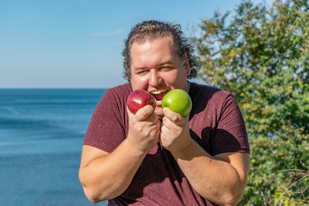Homme gras drôle sur l'océan manger des fruits
 - Photo, image