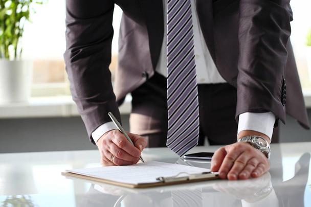 Mužská paže v obleku a kravatě vyplněný formulář připnutý na podložku - Fotografie, Obrázek