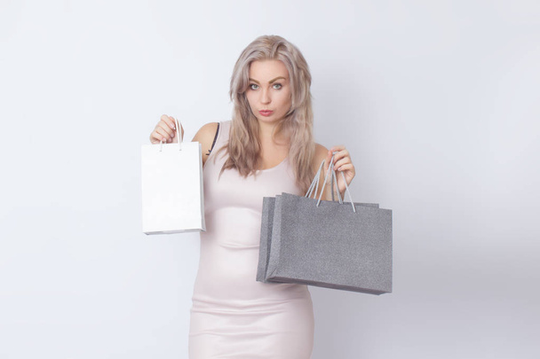 Closup studio portrait of stylish blonde woman over white background. Concept: Shopping. Woman with bags in borth hands - Fotó, kép