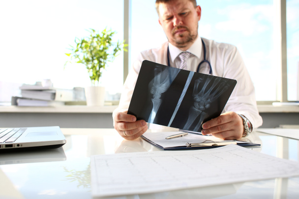 Arzt hält silbernen Stift im Arm und schaut sich Röntgenbild an - Foto, Bild