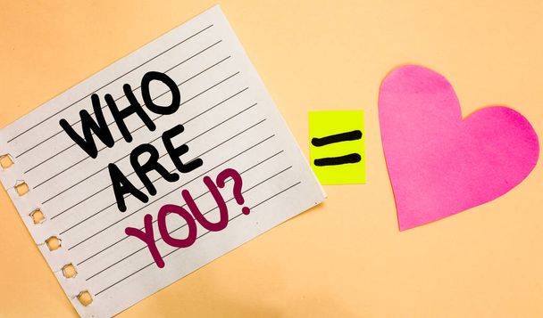 Text sign showing Who Are You question. Conceptual photo Identify yourself description personal characteristics Transverse white paper with words equal love heart on Peach color base. - Photo, Image