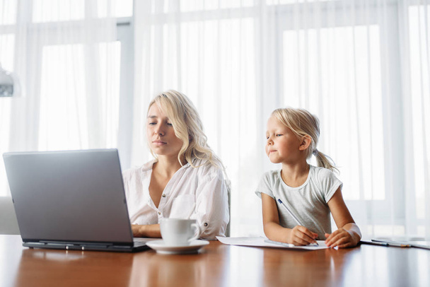 Maman utilise un ordinateur portable à la maison, l'enfant la regarde. Sentiment parental, convivialité, famille heureuse
 - Photo, image