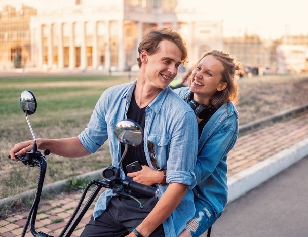 Preciosa pareja joven conduciendo bicicleta eléctrica durante el verano
 - Foto, Imagen
