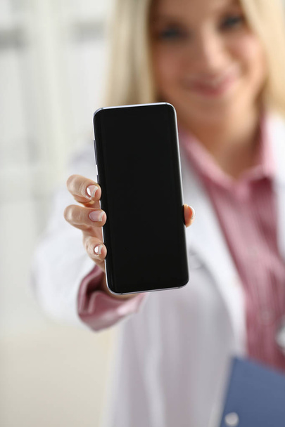Bela mulher loira médico segurando smartphone
 - Foto, Imagem