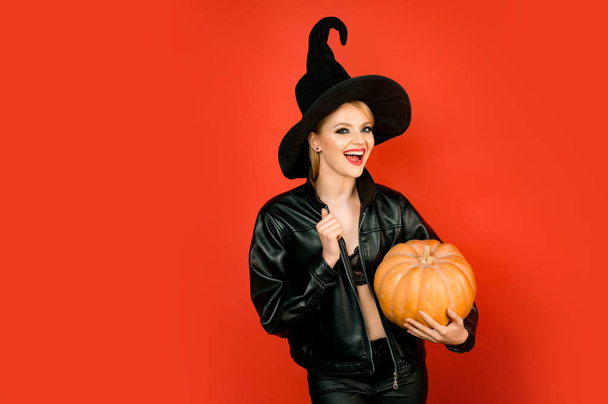 boldog halloweent. Fiatal nők fekete boszorkány halloween jelmez párt felső piros háttér. Boszorkány jelentő sütőtökkel. - Fotó, kép