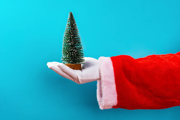 Babbo Natale che tiene un modello di albero di Natale davanti a uno sfondo blu
 - Foto, immagini