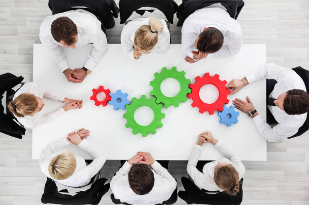 Business problem solution, mechanism of business, teamwork concept, business team sitting around white table with cogs - Fotografie, Obrázek