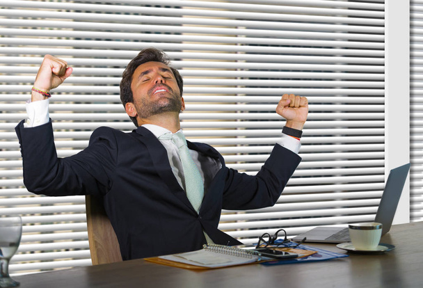 спосіб життя корпоративна компанія портрет молодого щасливого і успішного бізнесмена, який працює в сучасному офісі, сидячи за віконним комп'ютерним столом, святкуючи перемогу в успіху фінансової роботи
  - Фото, зображення