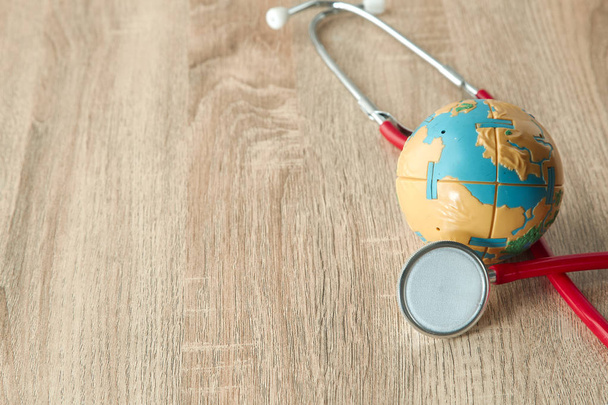 World Earth Day April 22, 2019 and World health day, April 7 concept. earth with red Stethoscope on wooden table background texture. Empty space for design,Soft sunlight - Photo, Image