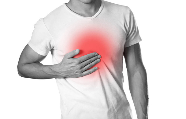 The man is holding his chest. Chest pain. Heartburn. The hearth is highlighted in red. Close up. Isolated on white background. - Photo, Image