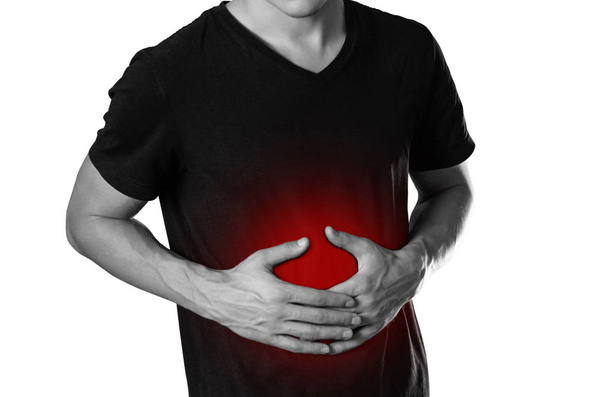 Muž drží jeho žaludek. Bolest břicha. Ohniště je zvýrazněn červeně. Zblízka. Izolované na bílém pozadí. - Fotografie, Obrázek