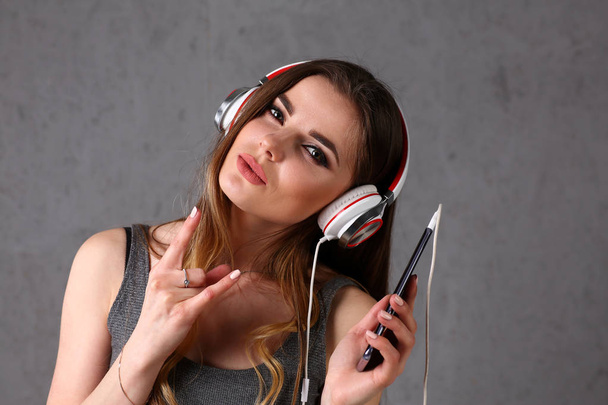 Woman in headphones holding smartphone - Valokuva, kuva