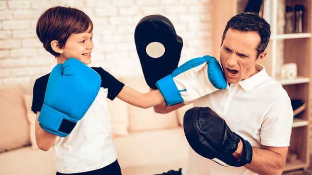 Boy Standing. Father and Son Boxer. Sport at Home. Warm Up in Quarter. Boxing Supplies in Hands. Boxing Gloves. Doing Sports. Man and Boy Train at Home. Child in Boxing Gloves in Apartment. Little Boy - Photo, Image