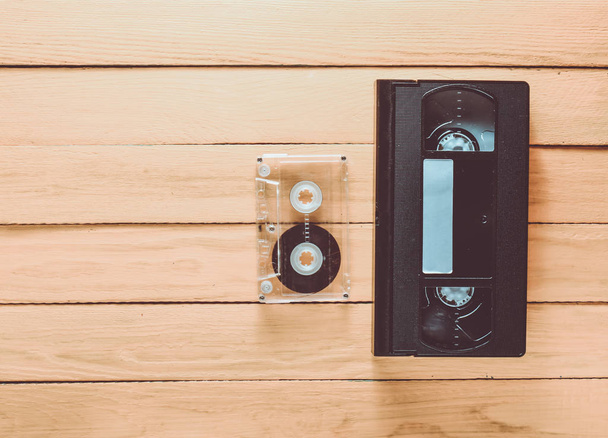Kaseta video VHS i kasecie audio, na żółtym tle drewnianych. Technologii mediów retro z lat 80. Widok z góry. - Zdjęcie, obraz