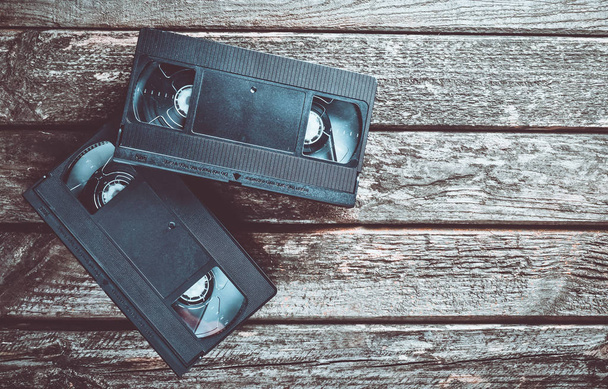 Dwa plastikowe kasety wideo z lat 80 na rustykalne drewnianym stole. Widok z góry. - Zdjęcie, obraz