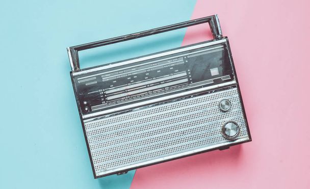 Retro-Radioempfänger auf rosa-blauem Pastellgrund. Medientechnik 60er Jahre. Ansicht von oben. - Foto, Bild