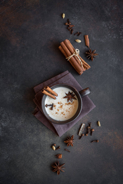 Tè tradizionale indiano masala chai in tazza di ceramica con ingredienti. Tè nero piccante con latte su sfondo scuro rustico, spazio copia
. - Foto, immagini