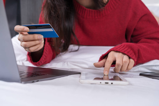 vrouw met behulp van Tablet PC voor online winkelen met credit card op een bed - Foto, afbeelding