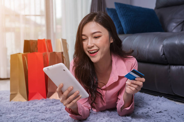 fröhliche Frau nutzt digitales Tablet für Online-Einkäufe mit Kreditkarte im Wohnzimmer - Foto, Bild