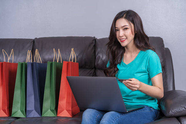 счастливая женщина, использующая ноутбук для онлайн-покупок с кредитной картой в гостиной
 - Фото, изображение