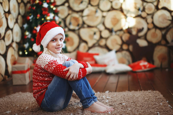 Junge mit Weihnachtsmützen liegen und lachen auf dem Teppich neben dem Neujahrsbaum im Hintergrund der Baumfällungen. - Foto, Bild