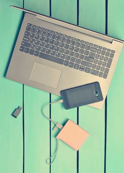 Φορητό υπολογιστή, smartphone, τράπεζα δύναμης, μονάδα flash Usb, σε ένα μπλε ξύλινο τραπέζι. Σύγχρονες ψηφιακές συσκευές και gadgets. Το Top view.  - Φωτογραφία, εικόνα