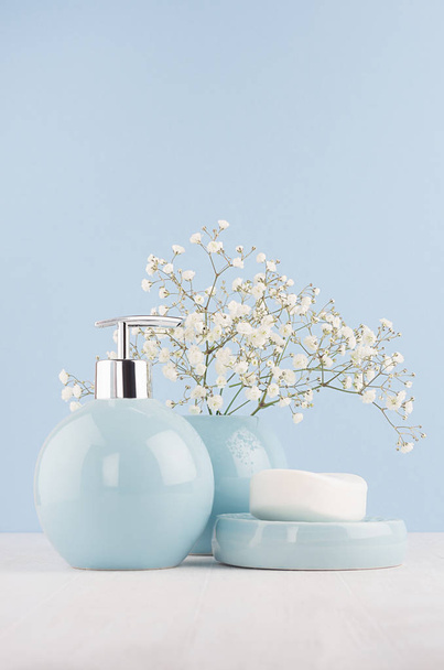 Soft light fresh bathroom interior in pastel blue color with white bouquet and smooth ceramic bowls on wood table, vertical. - Foto, Imagen