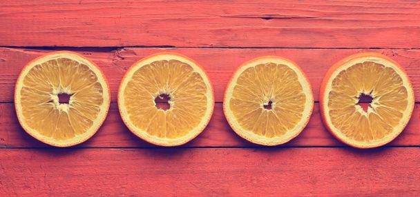 Sušené plátky pomeranče na oranžové dřevěné pozadí. Pohled shora. - Fotografie, Obrázek