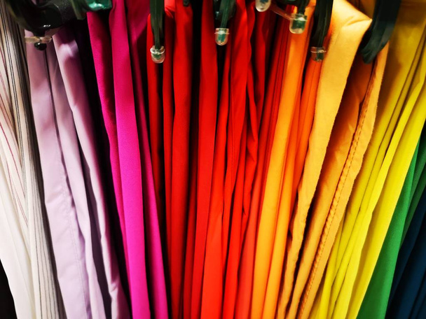 kleding en veelkleurige broek in gradeation opknoping op display - Foto, afbeelding