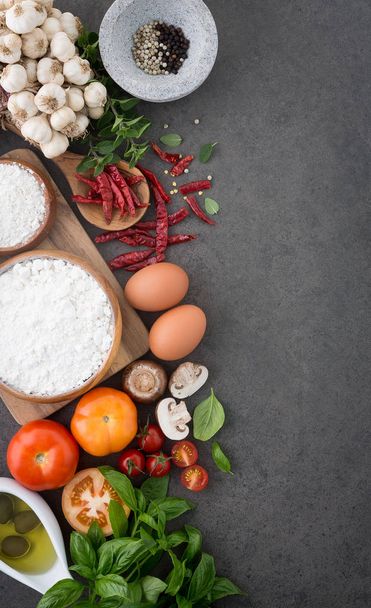 イタリア料理の背景、トマト、バジル、キノコ、オリーブ、オリーブ オイル、ニンニク、胡椒、唐辛子、卵、小麦粉、オレガノで。スレートの背景. - 写真・画像