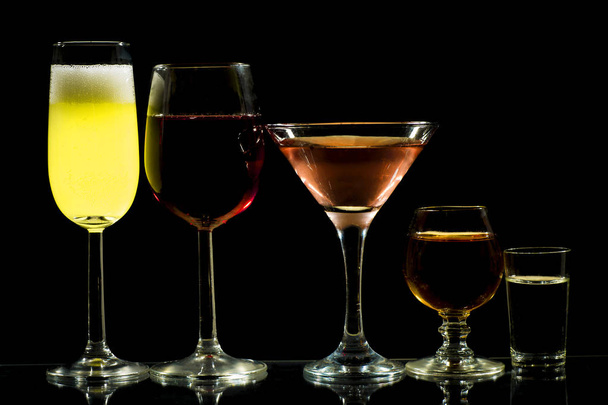 A collection of spirits and glasses for drinks on a dark background - Foto, Imagem