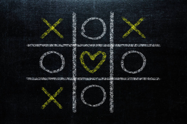 Abstract Tic Tac Toe Game Competition with heart shape in the center. XO Win Challenge Concept on black board - Foto, Imagem
