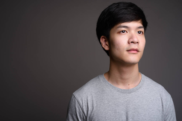 Fiatal csinos ázsiai férfi gondolkodás sötétszürke háttérrel - Fotó, kép