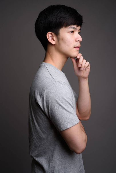 Profile view of young handsome Asian man thinking - Foto, Imagen