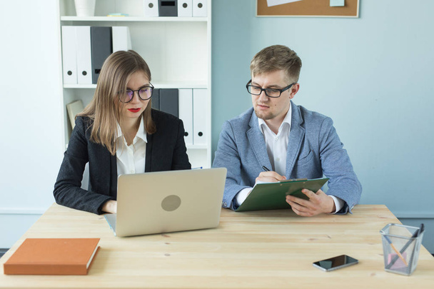 Business, teamwork and people concept - woman and man are working together in office - Photo, Image