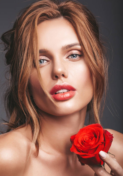 Retrato de moda de belleza de la joven modelo rubia con maquillaje natural y piel perfecta con hermosa rosa posando en el estudio
 - Foto, imagen