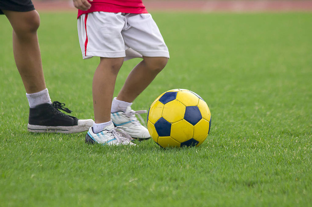 Las piernas de los niños están pateando el fútbol
. - Foto, Imagen