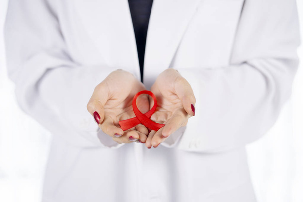 Closeup of unknown female doctor hand holding a world AIDS day awareness ribbon on her palms - Fotografie, Obrázek