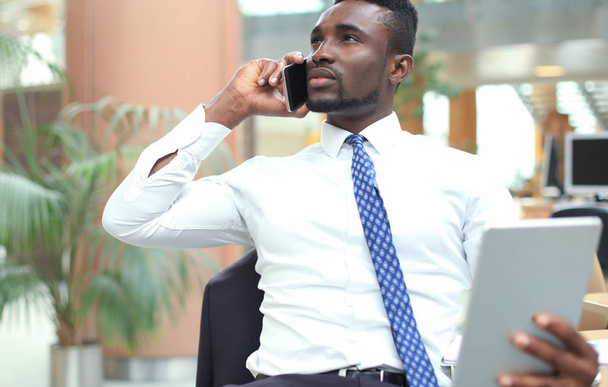 Successful african american entrepreneur using tablet computer and talking on phone. - Fotó, kép