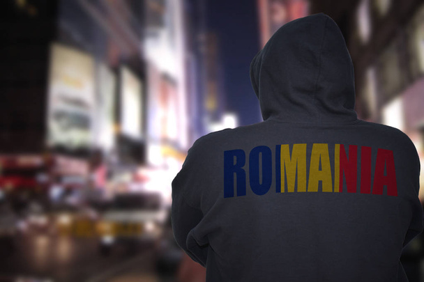 επικίνδυνος άνθρωπος που στέκεται στο δρόμο το βράδυ με μαύρο hoodie της πόλης με τη Ρουμανία κείμενο στην πλάτη του - Φωτογραφία, εικόνα