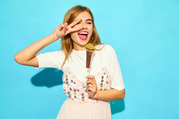 Young beautiful woman singing with props fake microphone. Trendy girl in casual summer clothes. Positive female emotion facial expression body language. Funny model isolated on blue background - Photo, image