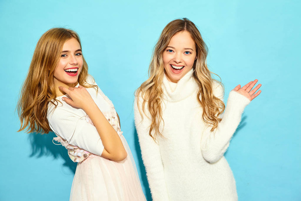 Két fiatal szép mosolygó hipster lányok trendi nyári fehér ruha. Szexi, gondtalan nő pózol kék fal közelében. Pozitív minták - Fotó, kép