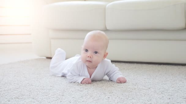 glückliches Baby auf Teppich liegend, lächelndes Säuglingsmädchen in weißer Kleidung - Filmmaterial, Video