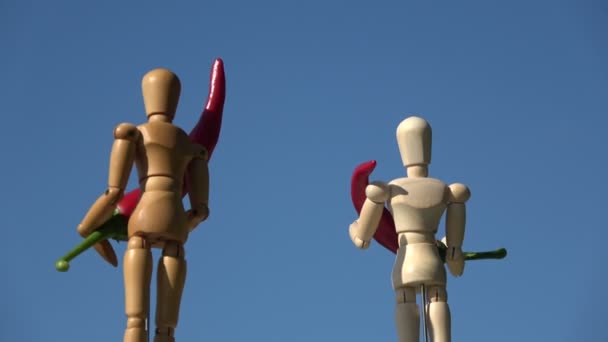 Rotující dvě dřevěné umělec figuríny figuríny na pozadí oblohy a držení červené horké chilli papričky - Záběry, video