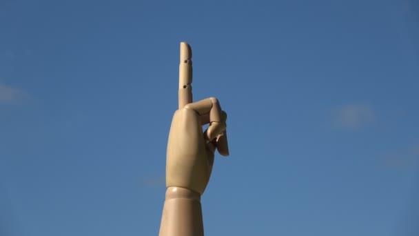 Wooden hand finger symbols  concept middle finger sign in  gesture meaning fuck you or fuck off rotating on blue sky background - Footage, Video
