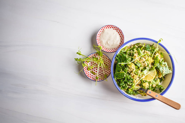 Kale, quinoa, avocado vegan salad in a white bowl on a white background. Plant based diet concept. - Fotó, kép