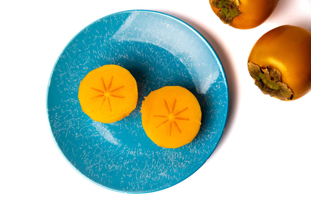 Persimmon kaki fruit on a plate isolated on white - Φωτογραφία, εικόνα