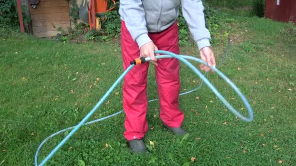 gardener in autumn yard wrap rubber blue water hose - Footage, Video
