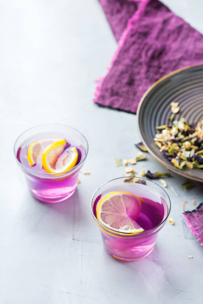 Фиолетовый чай из гороха бабочки в стакане на столе. Здоровый детоксикации фитнес-напиток, напитки
 - Фото, изображение